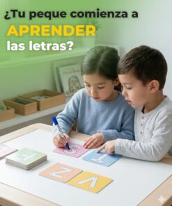 Vista de cerca de dos niños interactuando con tarjetas del abecedario, trazando la letra S con marcador borrable sobre un escritorio de madera.