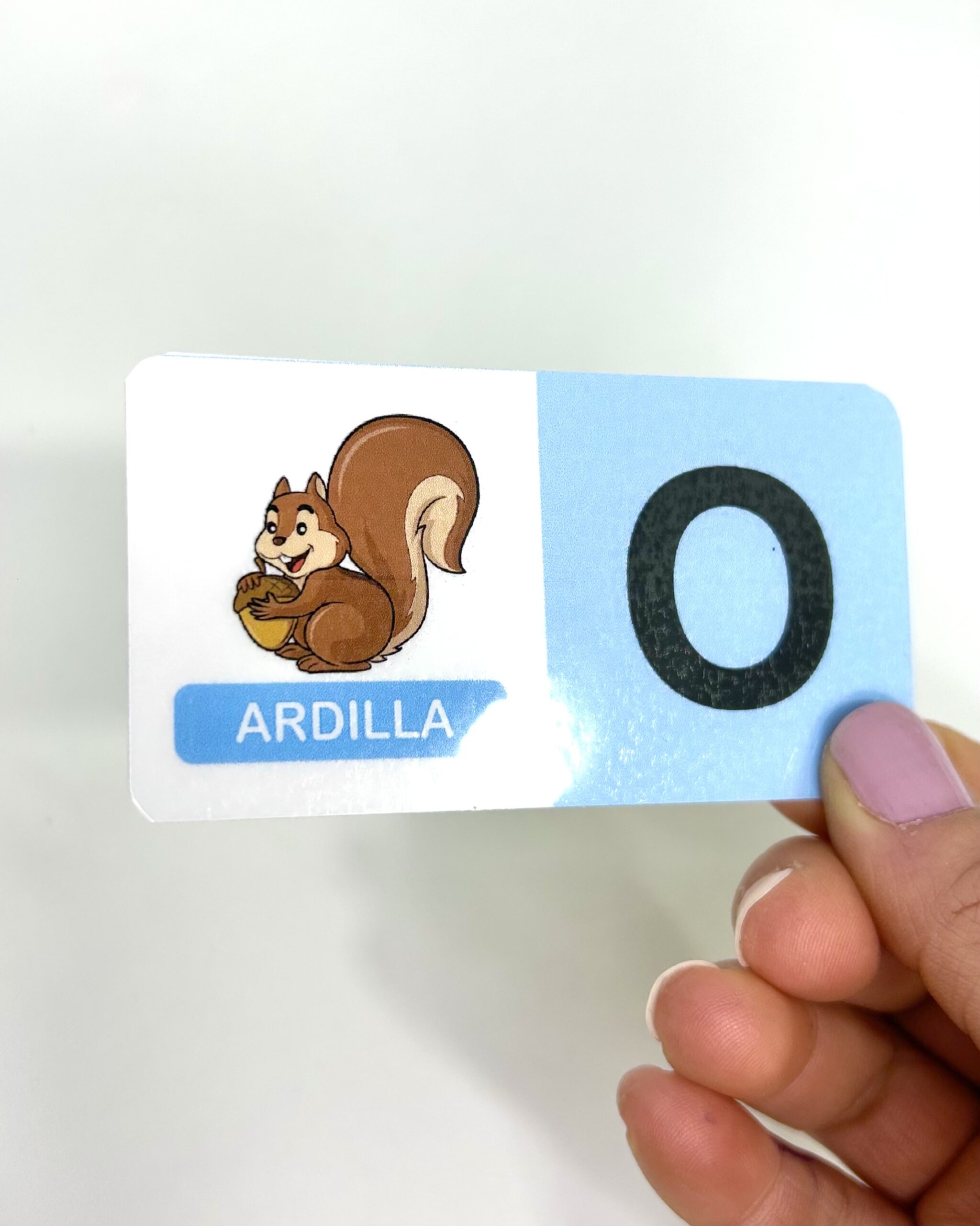 Primer plano de una ficha del dominó Domizoo con la ilustración de una ardilla y la letra O sobre fondo claro.