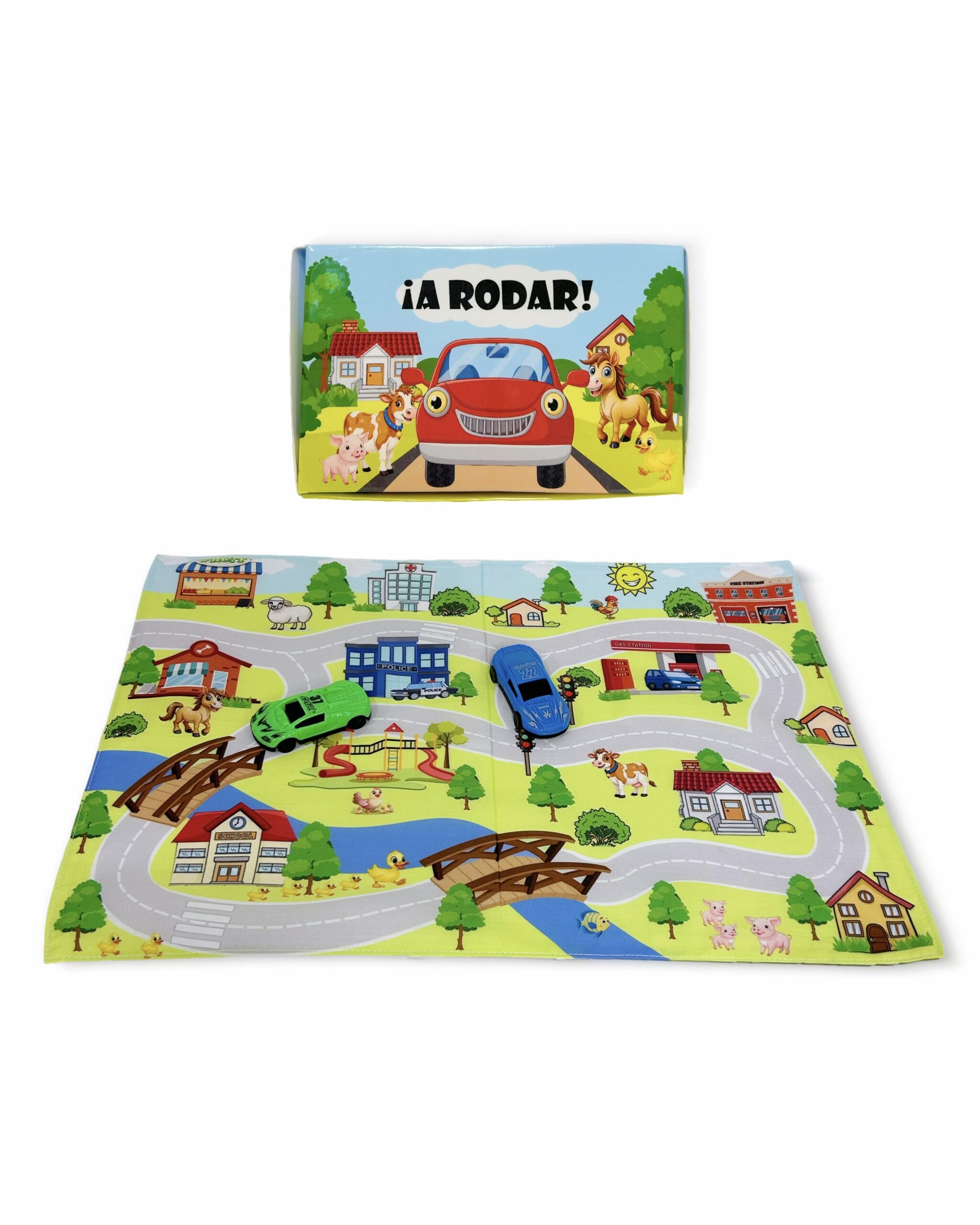 Caja del juego A Rodar junto a un tapiz de tela desplegado con diseño de ciudad, calles, puentes y dos autitos de juguete.