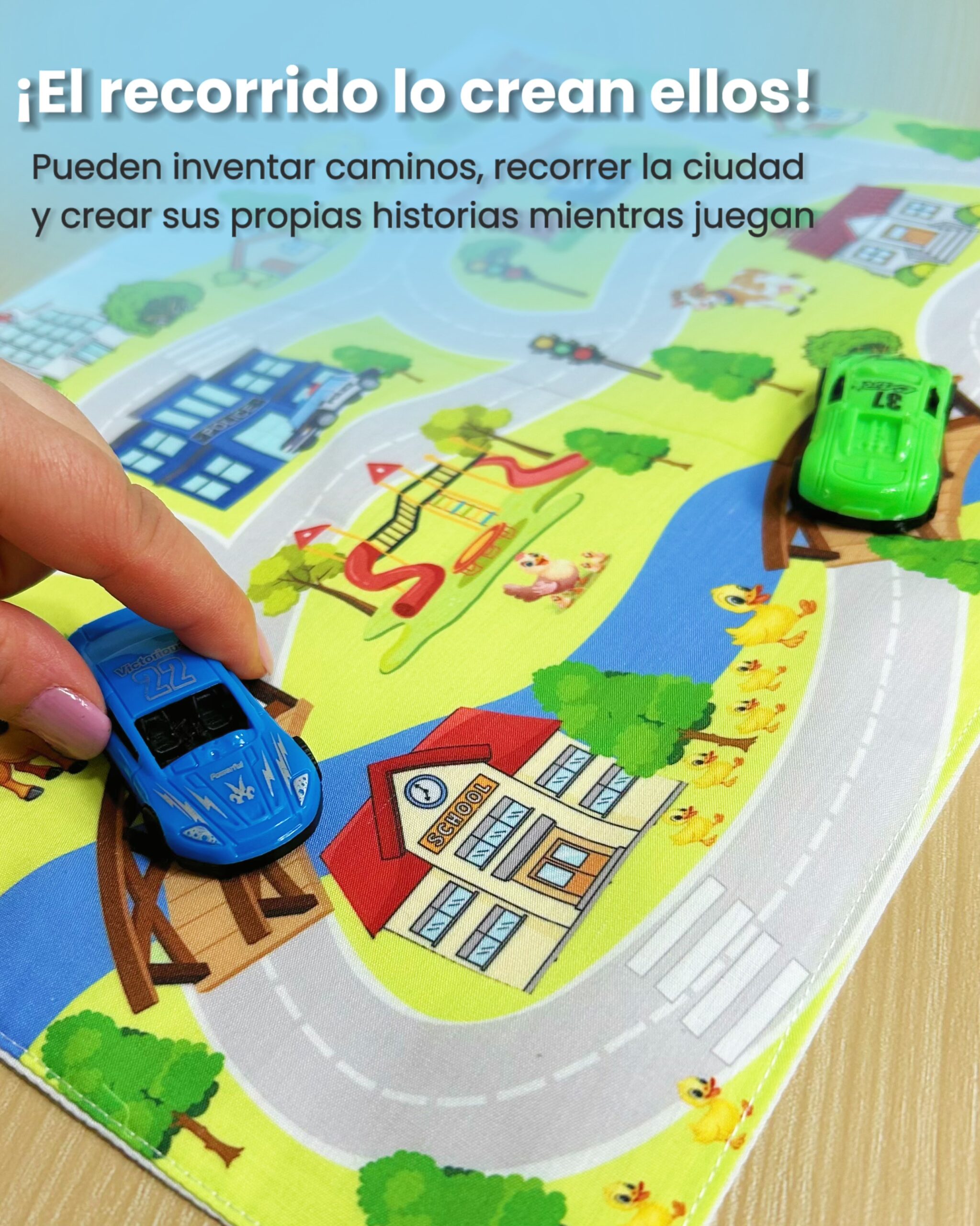 Mano moviendo un autito azul de juguete sobre el puente de un tapiz interactivo de tela con ilustración de río y escuela.