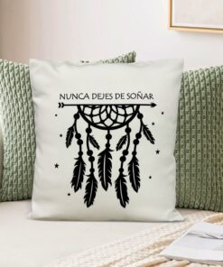 Almohadón crema personalizado con dibujo de atrapasueños y frase "nunca dejes de soñar", sobre sillón gris y fondo interior