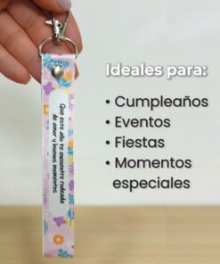 Mano sosteniendo un llavero de cinta rosa con estampado floral y texto Ideal para cumpleaños, eventos y momentos especiales.